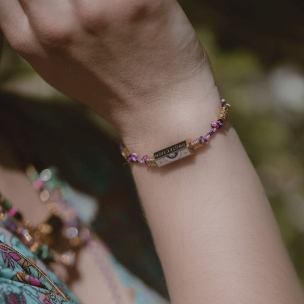 bracelet protection acier inoxydable dore sur cordon tresse fuschia, marine, blanc et violet